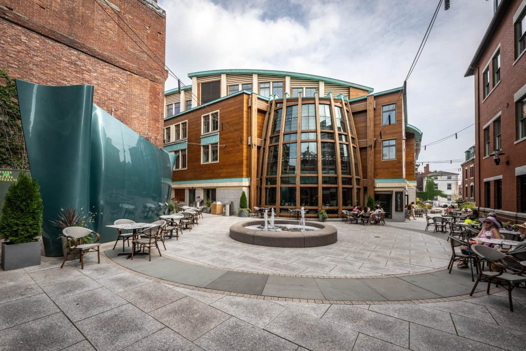 Brick and paver plaza with a fire feature and seating outside a modern building