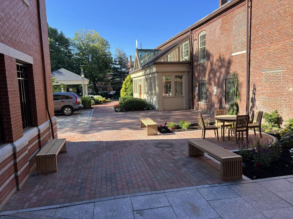 Brick paver courtyard between downtown buildings with benches and planted beds