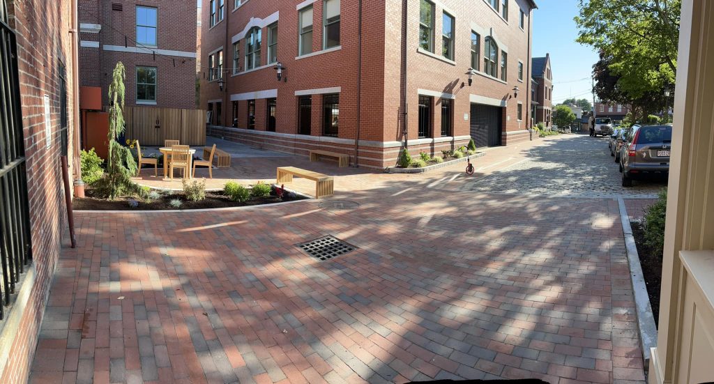Brick paver street surface between downtown buildings with a drainage grate set flush
